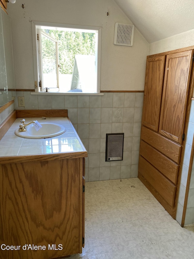 185 King St, Wallace, ID 83873 - bathroom with vaulted ceiling, vanity, tile patterned floors, tile walls, and a textured ceiling