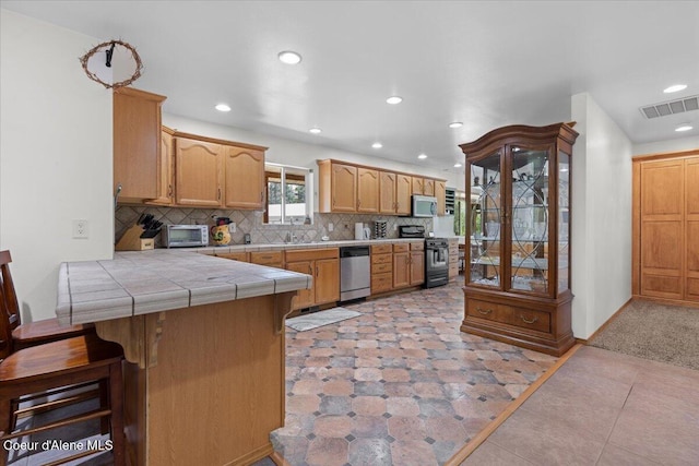 174 Where Its At Rd, Athol, ID 83801 - kitchen featuring stainless steel appliances, tile counters, recessed lighting, a peninsula, and decorative backsplash