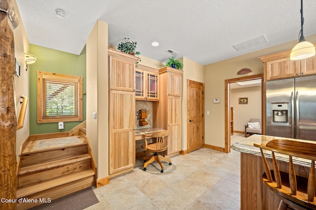 1911 Carr Creek Rd, Sandpoint, ID 83864 - kitchen with stainless steel fridge, an office area, light brown cabinetry, glass insert cabinets, and hanging light fixtures