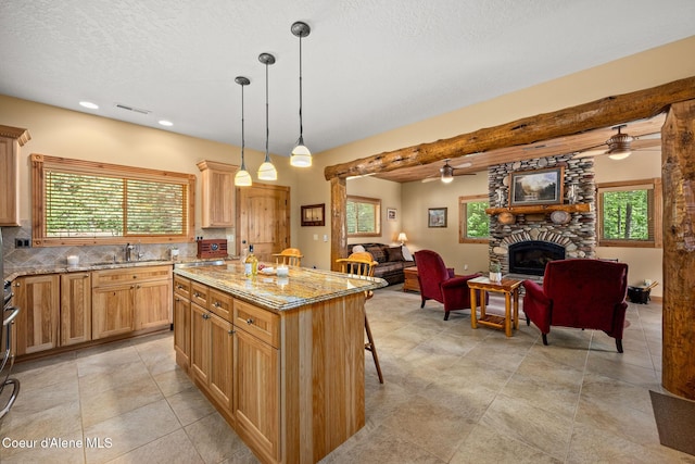 1911 Carr Creek Rd, Sandpoint, ID 83864 - kitchen featuring open floor plan, a stone fireplace, light stone countertops, a kitchen bar, and healthy amount of natural light