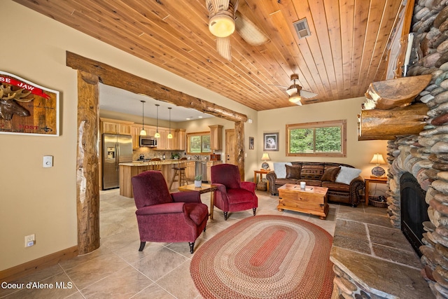 1911 Carr Creek Rd, Sandpoint, ID 83864 - living area featuring a ceiling fan, plenty of natural light, a fireplace, light tile patterned floors, and wood ceiling