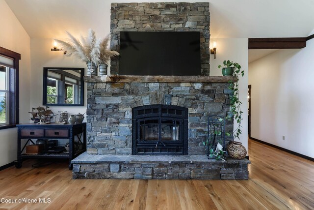 1010 Mc Quade Gulch Dr, Clark Fork, ID 83811 - living area featuring wood finished floors, a stone fireplace, and vaulted ceiling