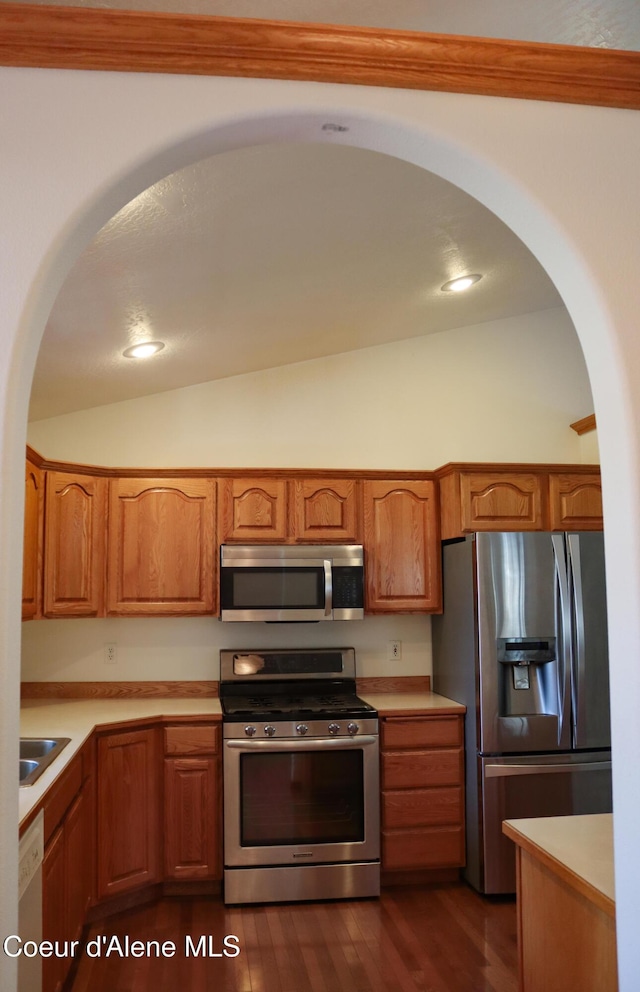 1276 W Edgewood Cir, Coeur Dalene, ID 83815 - kitchen with appliances with stainless steel finishes, arched walkways, vaulted ceiling, light countertops, and brown cabinets