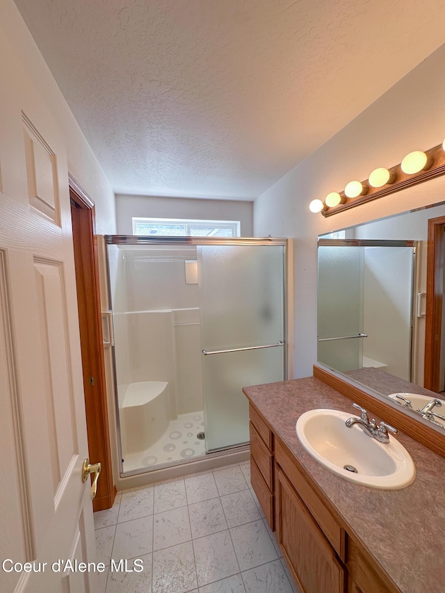 1276 W Edgewood Cir, Coeur Dalene, ID 83815 - bathroom featuring a stall shower, vanity, and a textured ceiling