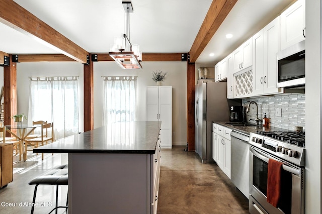 1106 Larch St Unit A, Sandpoint, ID 83864 - kitchen with appliances with stainless steel finishes, beamed ceiling, backsplash, a center island, and finished concrete floors