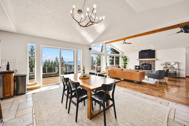 1273 S Grouse Meadow Dr, Coeur Dalene, ID 83814 - dining area featuring lofted ceiling, a stone fireplace, a chandelier, light tile patterned floors, and a ceiling fan