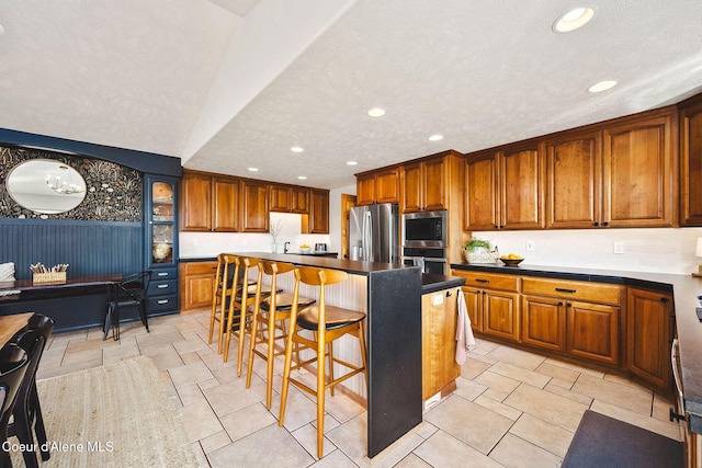 1273 S Grouse Meadow Dr, Coeur Dalene, ID 83814 - kitchen featuring stainless steel appliances, a breakfast bar, brown cabinets, recessed lighting, and a kitchen island