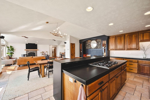 1273 S Grouse Meadow Dr, Coeur Dalene, ID 83814 - kitchen with stainless steel gas stovetop, dark countertops, brown cabinets, vaulted ceiling, and a center island