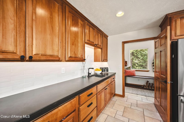 1273 S Grouse Meadow Dr, Coeur Dalene, ID 83814 - kitchen with freestanding refrigerator, dark countertops, decorative backsplash, brown cabinetry, and recessed lighting