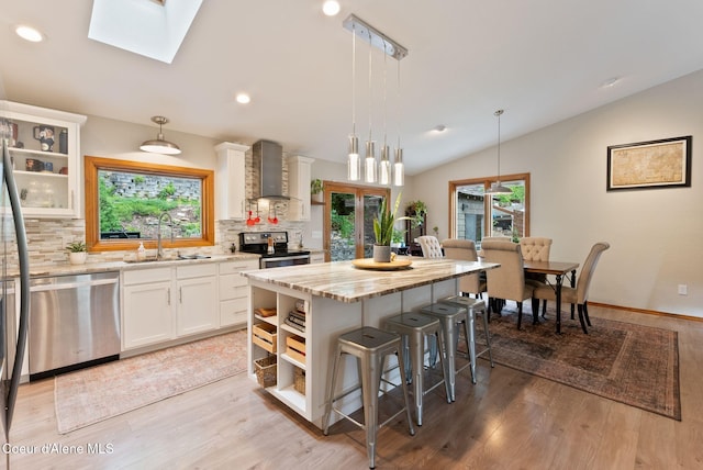 3011 E Fernan Ct, Coeur Dalene, ID 83814 - kitchen with open shelves, appliances with stainless steel finishes, wall chimney exhaust hood, a kitchen bar, and lofted ceiling