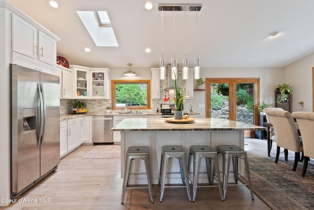 3011 E Fernan Ct, Coeur Dalene, ID 83814 - kitchen with appliances with stainless steel finishes, a skylight, a kitchen bar, tasteful backsplash, and white cabinets