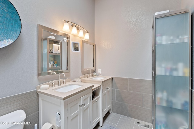 3011 E Fernan Ct, Coeur Dalene, ID 83814 - full bath featuring tile walls, two vanities, a wainscoted wall, tile patterned flooring, and a textured wall