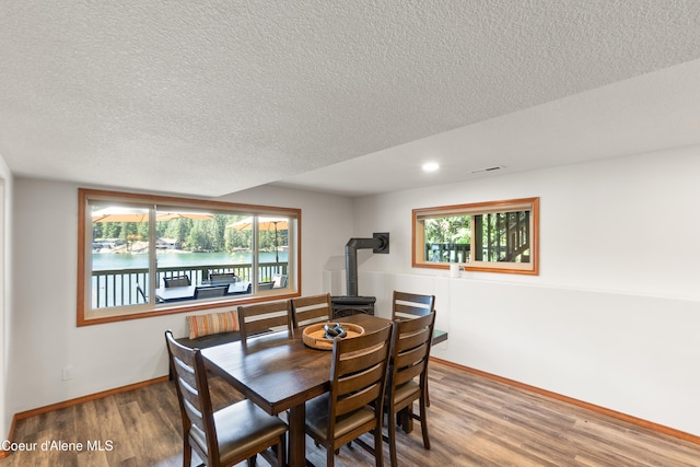 515 S Idaho St, Post Falls, ID 83854 - dining area with wood finished floors, a textured ceiling, and a wood stove