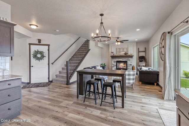 1546 N Tatum Dr, Post Falls, ID 83854 - dining area with stairs, light wood-style floors, a fireplace, a chandelier, and a ceiling fan