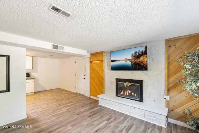 1024 W Mill Ave, Coeur Dalene, ID 83814 - unfurnished living room with a fireplace, a textured ceiling, wood finished floors, and wood walls