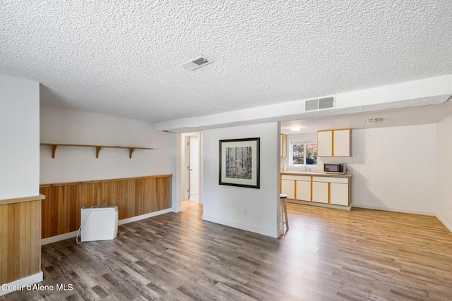 1024 W Mill Ave, Coeur Dalene, ID 83814 - unfurnished living room featuring a textured ceiling, wood finished floors, wainscoting, and wood walls