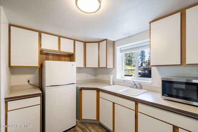 1024 W Mill Ave, Coeur Dalene, ID 83814 - kitchen with freestanding refrigerator, stainless steel microwave, wood finished floors, light countertops, and white cabinets