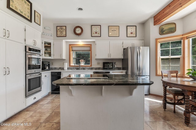 512 River Dr, Clark Fork, ID 83811 - kitchen with appliances with stainless steel finishes, white cabinetry, a kitchen island, a kitchen breakfast bar, and beam ceiling