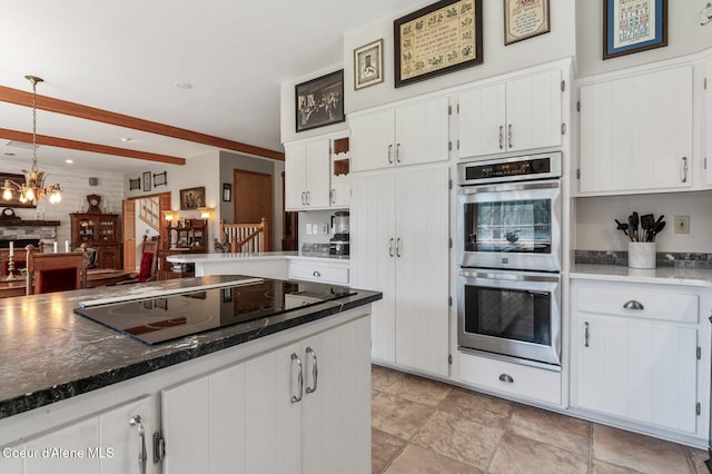512 River Dr, Clark Fork, ID 83811 - kitchen with stainless steel double oven, black electric stovetop, white cabinetry, a chandelier, and pendant lighting