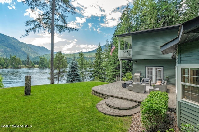 512 River Dr, Clark Fork, ID 83811 - view of green lawn with a balcony, a water and mountain view, outdoor lounge area, and a patio