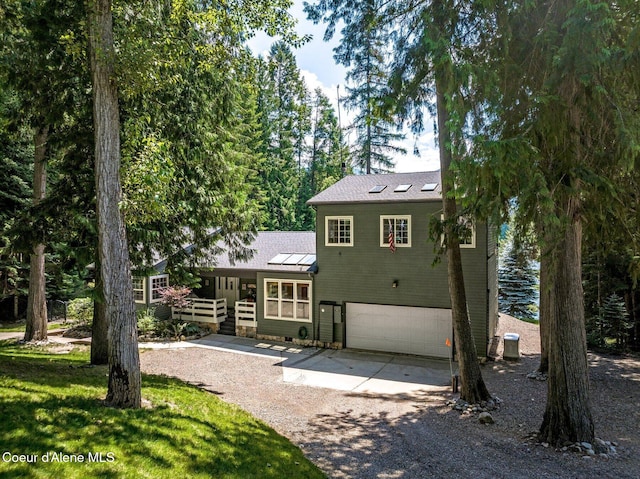 512 River Dr, Clark Fork, ID 83811 - rear view of house featuring dirt driveway, an attached garage, a standing seam roof, and a metal roof
