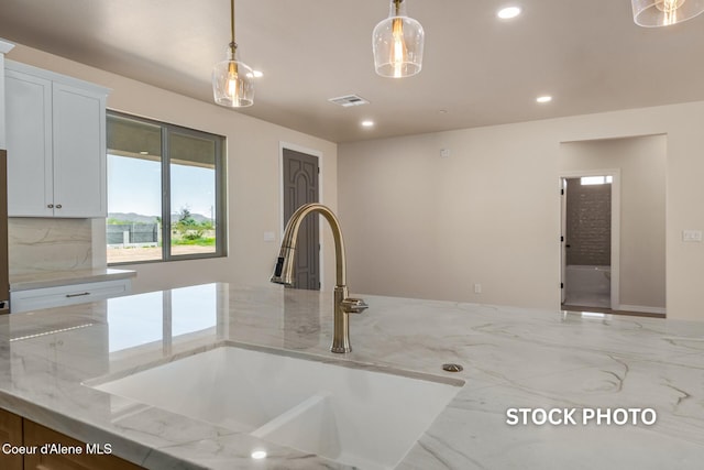 L1B1 Sylvan Rd, Athol, ID 83801 - kitchen featuring recessed lighting, decorative light fixtures, light stone countertops, tasteful backsplash, and white cabinets