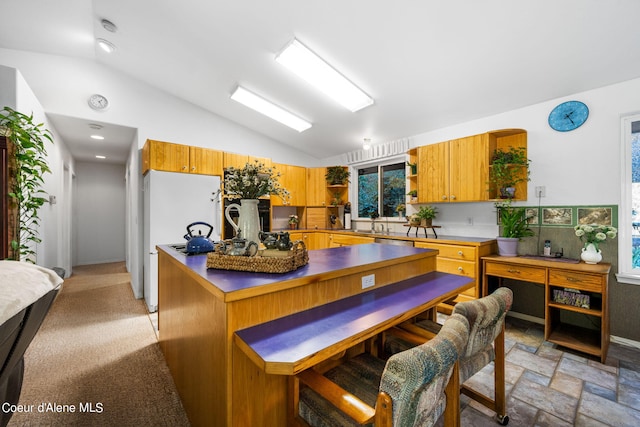 2711 S Carpenter Loop, Post Falls, ID 83854 - kitchen featuring lofted ceiling, open shelves, dark countertops, light stone finish floors, and freestanding refrigerator