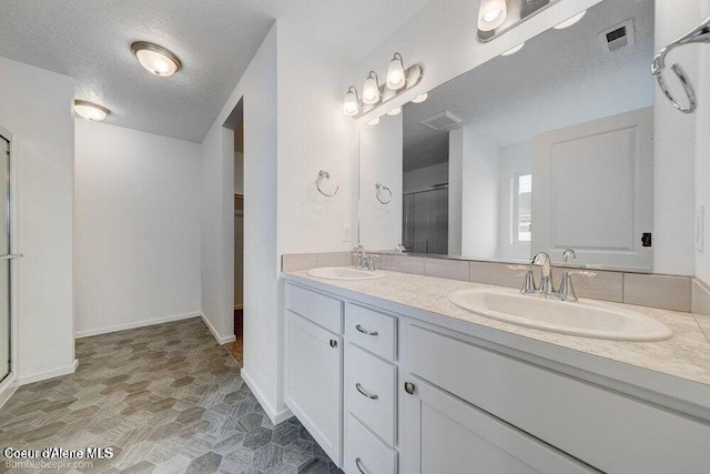 4300 N Arrowleaf Loop, Post Falls, ID 83854 - full bath featuring double vanity, a stall shower, a textured ceiling, stone finish floors, and a walk in closet