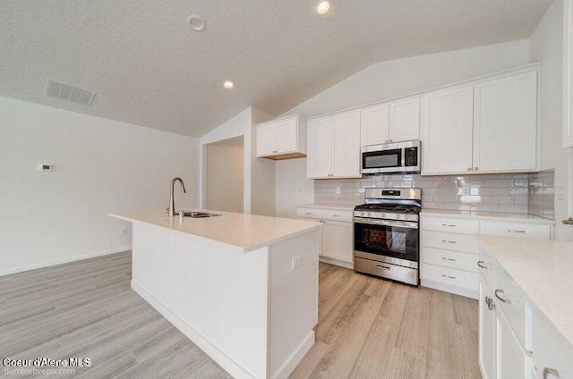 4300 N Arrowleaf Loop, Post Falls, ID 83854 - kitchen with appliances with stainless steel finishes, light wood-style floors, vaulted ceiling, white cabinets, and light countertops