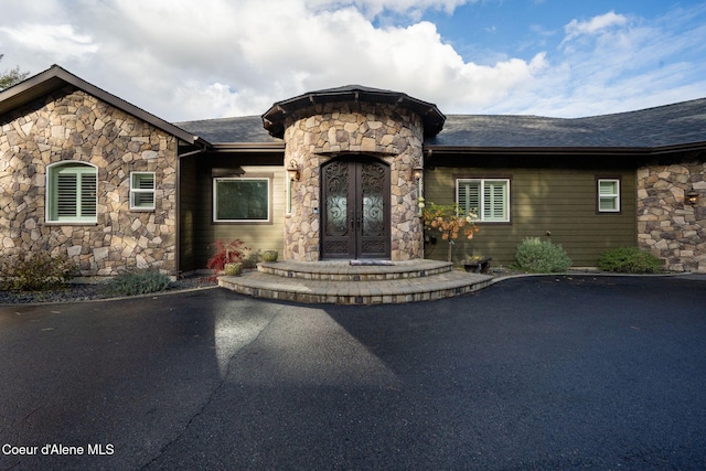 5969 W Highland Dr, Coeur Dalene, ID 83814 - view of front facade featuring stone siding, french doors, and roof with shingles