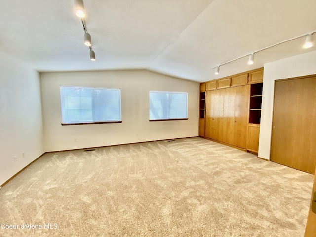 3674 E 2nd Ave, Post Falls, ID 83854 - unfurnished bedroom with rail lighting, light carpet, and lofted ceiling