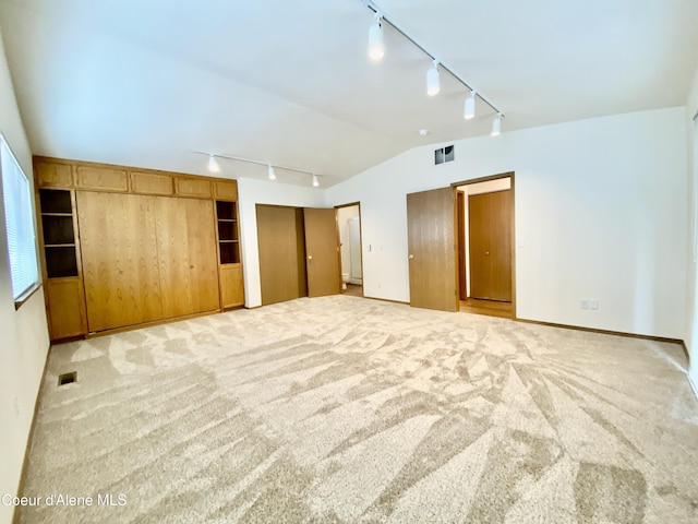 3674 E 2nd Ave, Post Falls, ID 83854 - unfurnished bedroom with rail lighting, light carpet, two closets, and lofted ceiling