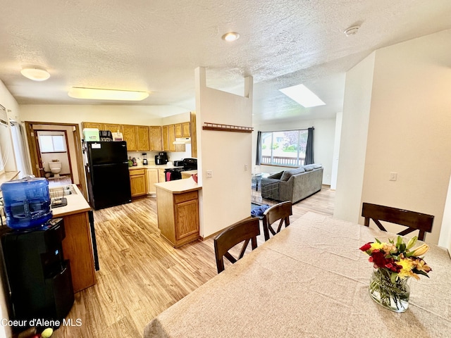 3674 E 2nd Ave, Post Falls, ID 83854 - kitchen with black appliances, under cabinet range hood, light countertops, a skylight, and light wood-type flooring