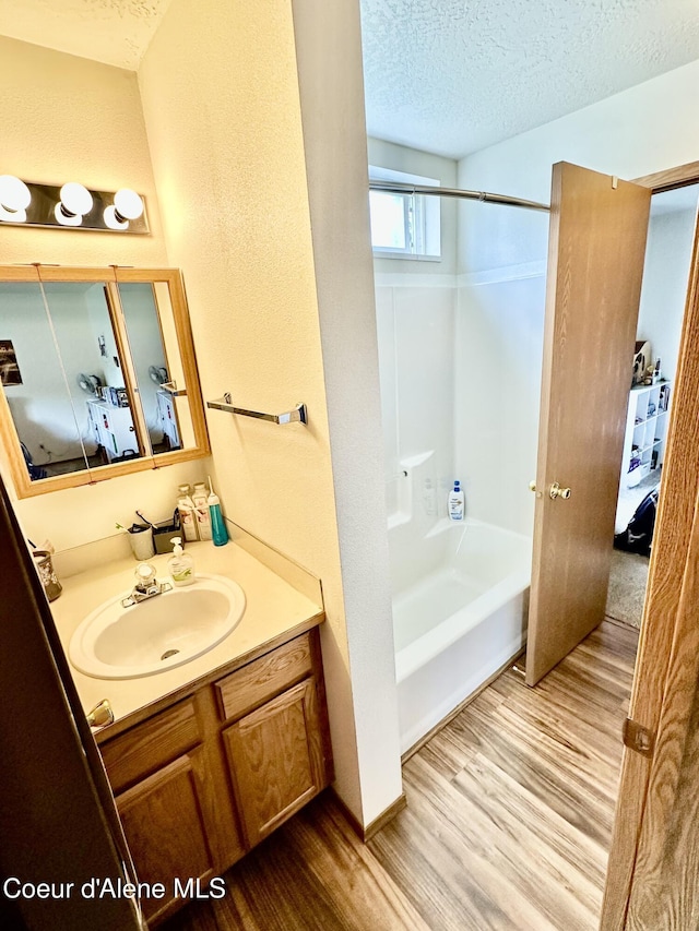 3674 E 2nd Ave, Post Falls, ID 83854 - bathroom featuring wood finished floors, vanity, ensuite bath, bathing tub / shower combination, and a textured ceiling