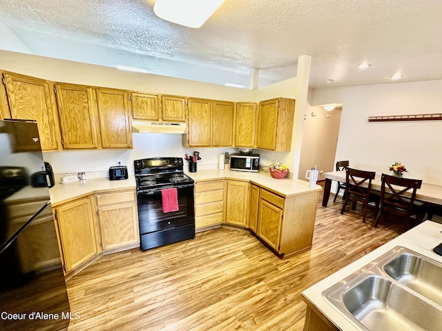 3674 E 2nd Ave, Post Falls, ID 83854 - kitchen featuring black appliances, under cabinet range hood, light countertops, light wood-style flooring, and a textured ceiling