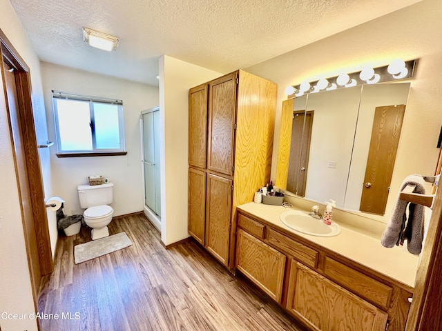 3674 E 2nd Ave, Post Falls, ID 83854 - bathroom featuring wood finished floors, a shower stall, vanity, and a textured ceiling