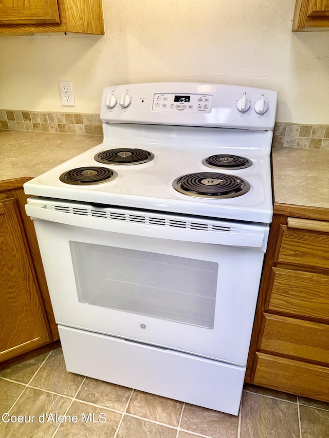 3674 E 2nd Ave, Post Falls, ID 83854 - kitchen with electric range, brown cabinetry, and light countertops