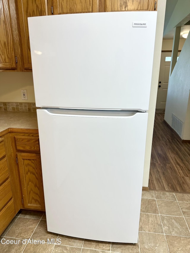 3674 E 2nd Ave, Post Falls, ID 83854 - kitchen view of freestanding refrigerator, brown cabinetry, and light countertops