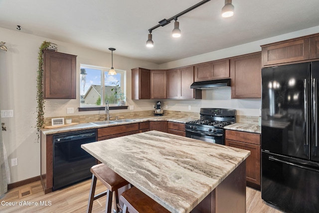 6595 W Covenant St, Rathdrum, ID 83858 - kitchen with black appliances, under cabinet range hood, light wood-type flooring, and light stone counters