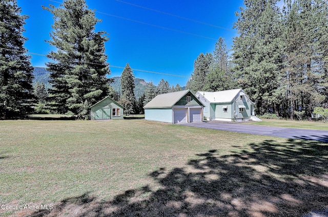 67 Nuchols Gulch Rd, Osburn, ID 83849 - view of property exterior featuring a yard, an outdoor structure, and view of wooded area