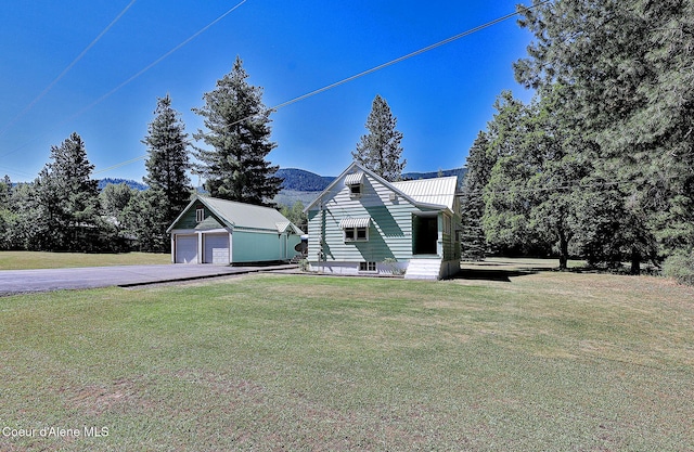 67 Nuchols Gulch Rd, Osburn, ID 83849 - view of front of house featuring an outdoor structure, a front lawn, a detached garage, and driveway