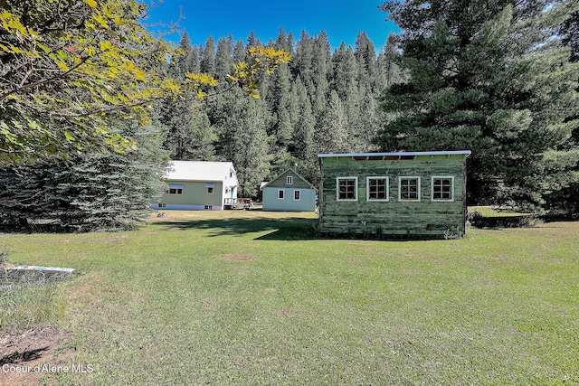 67 Nuchols Gulch Rd, Osburn, ID 83849 - view of green lawn with an outdoor structure and a forest view