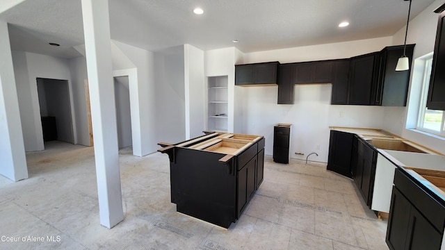 2003 E Plaza Ct, Post Falls, ID 83854 - kitchen featuring dark cabinets, a kitchen island, recessed lighting, and decorative light fixtures