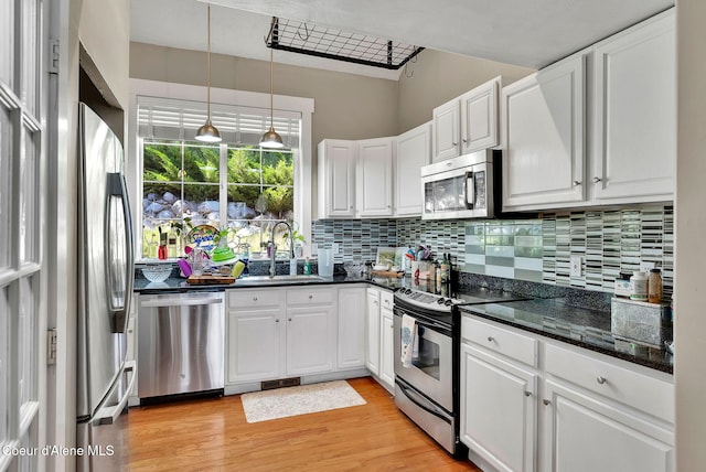959 N Rutledge Ct, Coeur Dalene, ID 83814 - kitchen with appliances with stainless steel finishes, white cabinetry, decorative backsplash, light wood-style floors, and pendant lighting