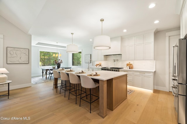 11551 N Bluejay Loop, Hayden, ID 83835 - kitchen with premium range hood, high quality fridge, light countertops, tasteful backsplash, and white cabinetry