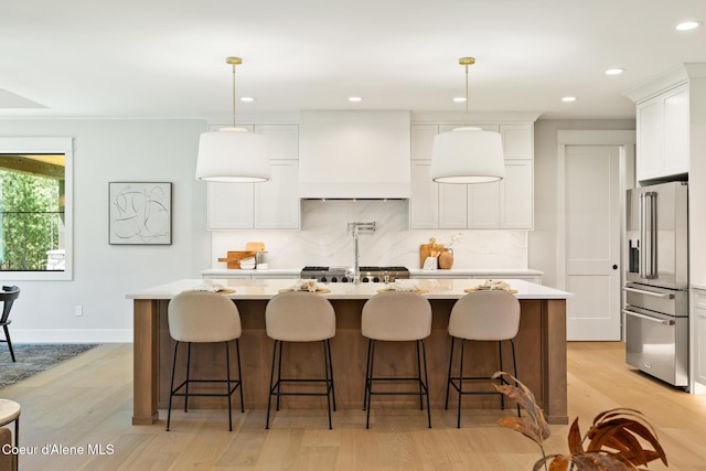 11551 N Bluejay Loop, Hayden, ID 83835 - kitchen featuring high end fridge, custom range hood, light countertops, light wood finished floors, and recessed lighting