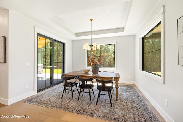 11551 N Bluejay Loop, Hayden, ID 83835 - dining room featuring a tray ceiling, wood finished floors, a chandelier, and healthy amount of natural light