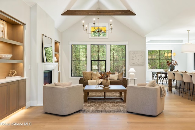 11551 N Bluejay Loop, Hayden, ID 83835 - living room with light wood-style flooring, a chandelier, a glass covered fireplace, and high vaulted ceiling