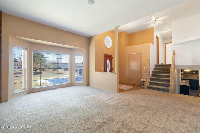 3206 N Lodgepole Rd, Coeur Dalene, ID 83815 - unfurnished living room with carpet flooring, a high ceiling, a ceiling fan, and stairs