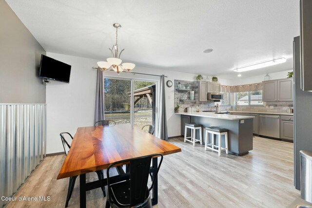 3206 N Lodgepole Rd, Coeur Dalene, ID 83815 - dining area with a chandelier, light wood-type flooring, and healthy amount of natural light